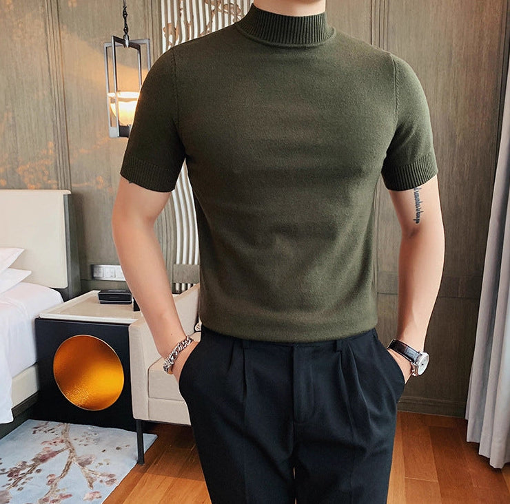 Person wearing a green turtleneck sweater and dark pants in a bedroom setting